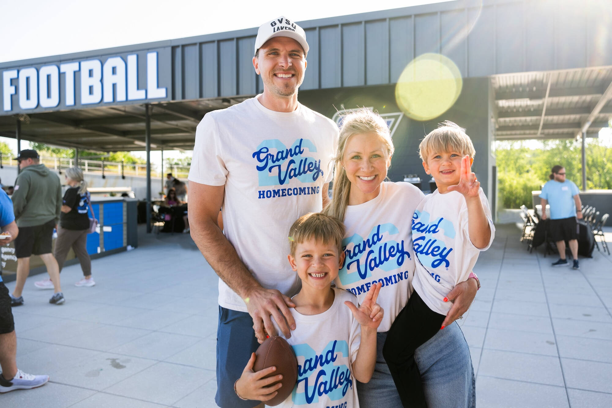 Laker family smiles in Lubbers Stadium wearing GVSU Homecoming t-shirts
